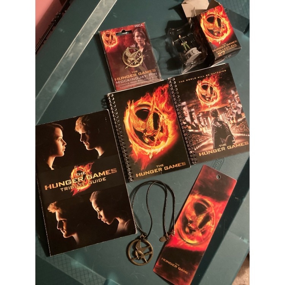 The Hunger Games Lot- book, figurine,necklace, pin, bookmark, 2 unused notebooks